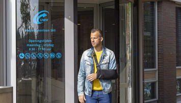 Man met sling loopt het UWV-gebouw uit