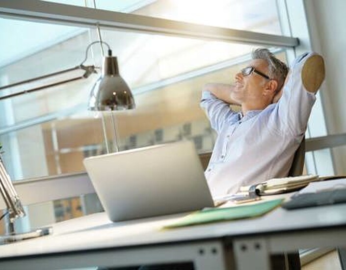 Man leunt achterover aan bureau