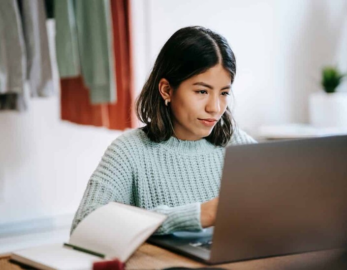 Vrouw in blauwe trui achter laptop