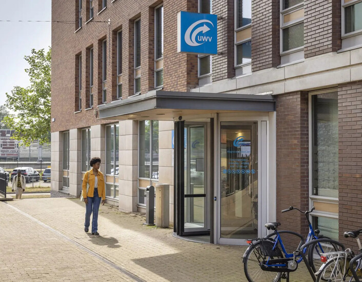 Vrouw in gele jas bij UWV-kantoor